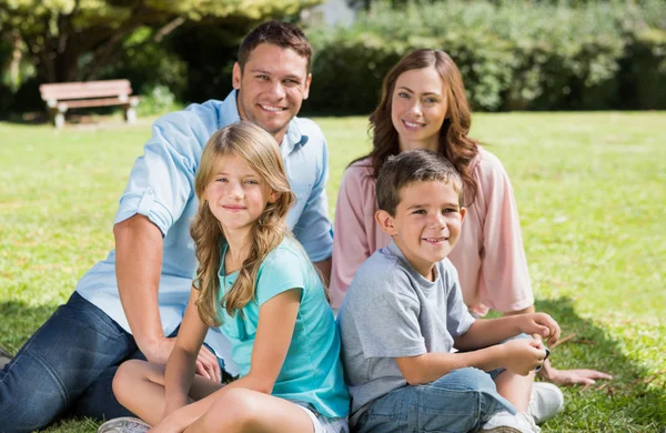 Familia sentada juntos sonriendo a la cámara — Foto de Stock