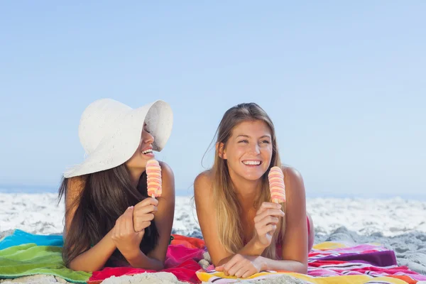 Mulheres bonitas sorridentes deitadas em sua toalha de praia — Fotografia de Stock