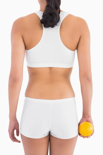 Cuerpo delgado femenino en ropa interior deportiva blanca sosteniendo naranja — Foto de Stock