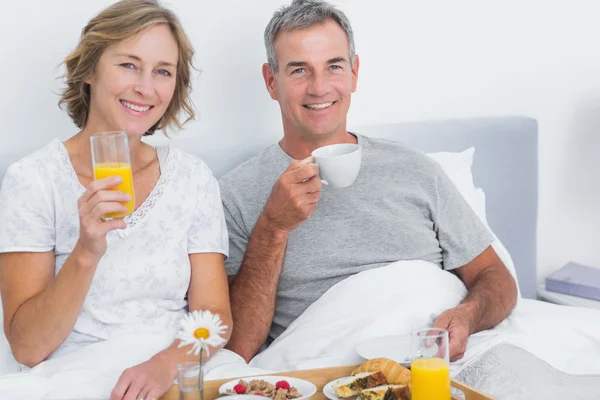 Веселая пара завтракает вместе в постели — стоковое фото