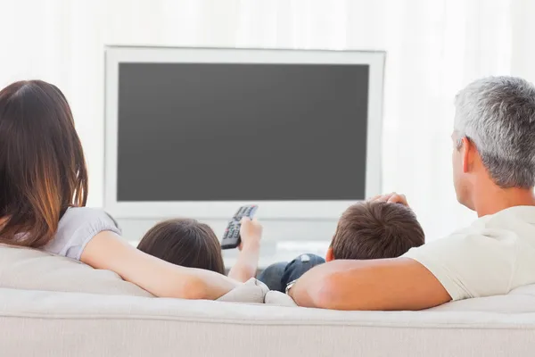 Rodzina siedzi na kanapie razem oglądanie telewizji — Zdjęcie stockowe