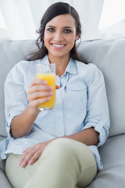 Sonriente morena ofreciendo zumo de naranja a la cámara — Foto de Stock
