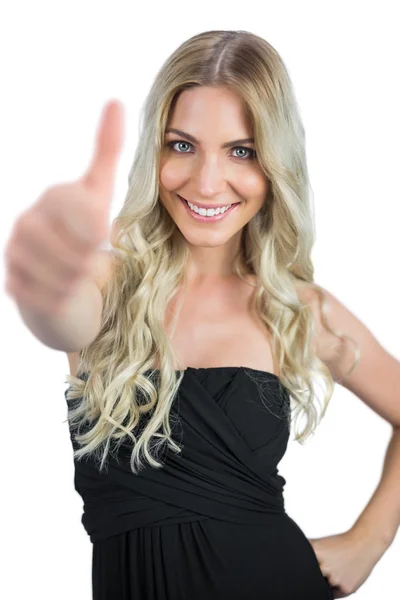 Smiling gorgeous blonde in black dress thumbs up — Stock Photo, Image