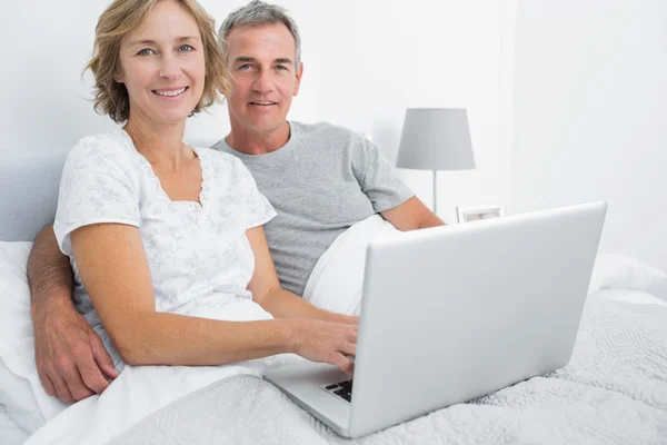 Casal relaxado usando seu laptop juntos na cama — Fotografia de Stock