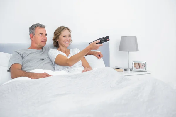 Χαρούμενο ζευγάρι βλέποντας τηλεόραση στο κρεβάτι — Φωτογραφία Αρχείου