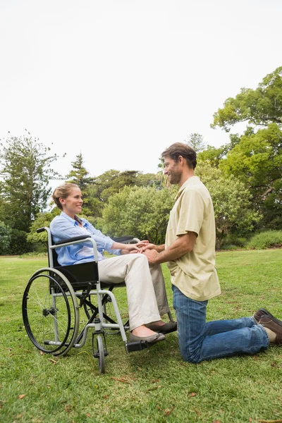 Mulher loira em cadeira de rodas com o parceiro ajoelhado ao lado dela — Fotografia de Stock