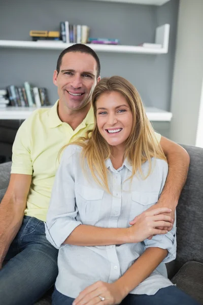 Casal feliz sentado em seu sofá — Fotografia de Stock