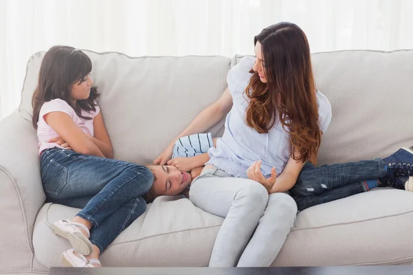 Malý chlapec leží na pohovce s jeho matkou a sestrou — Stock fotografie