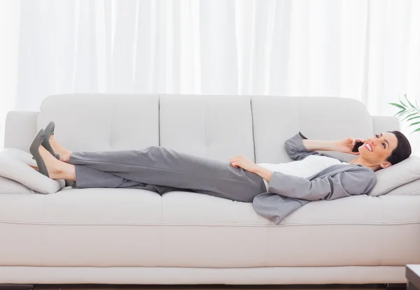 Pengusaha wanita berbaring di sofa menelepon dengan ponsel — Stok Foto