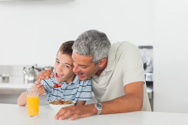 Батько і син їдять зернові під час сніданку — стокове фото