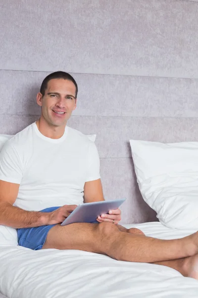 Hombre sonriente usando tableta pc en la cama — Foto de Stock