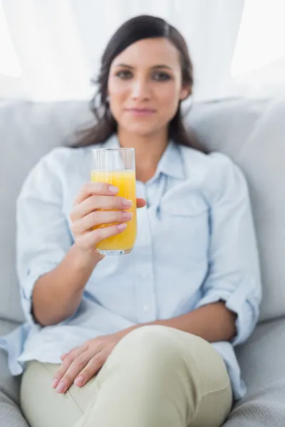 Morena pacífica oferecendo suco de laranja para a câmera — Fotografia de Stock