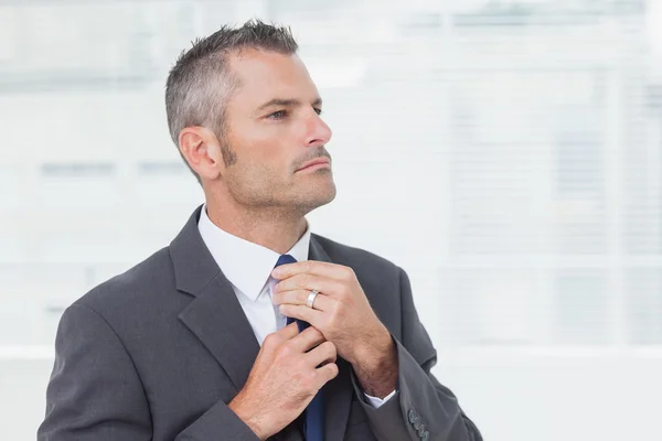 Empresário sério apertando sua gravata — Fotografia de Stock