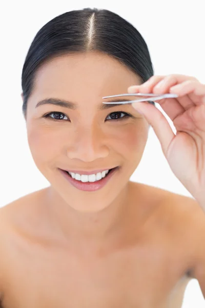 Smiling natural model using tweezers for her eyebrow — Stock Photo, Image