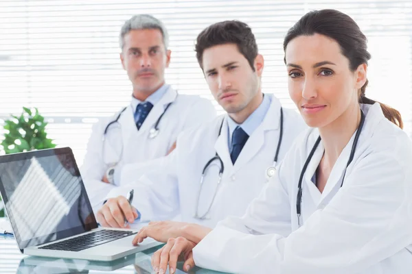 Serious doctors with laptop looking at camera — Stock Photo, Image