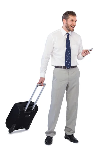 Широко улыбающийся бизнесмен с телефоном и чемоданом — стоковое фото