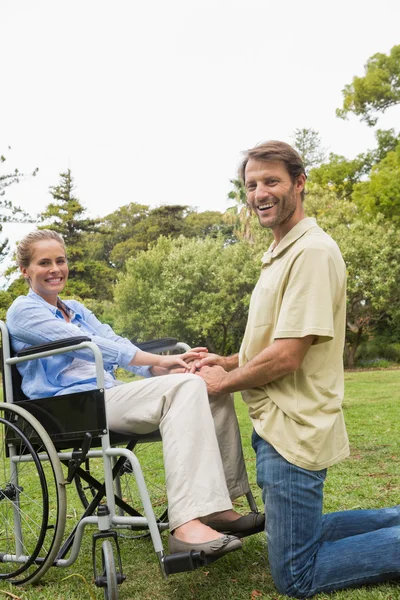 Blond kvinna ler i rullstol med partner knäböja bredvid — Stockfoto