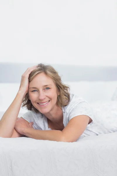 Lachende blonde vrouw liggend op bed — Stockfoto