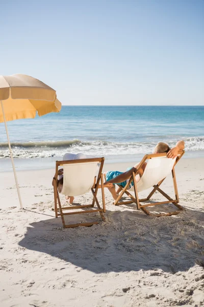 Happy couple sunbathing on their deck chairs — Stock Photo, Image