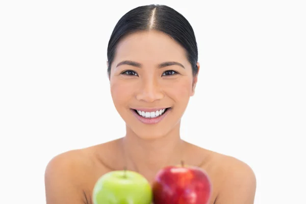Smiling brunette holding red and green apples — Stock Photo, Image