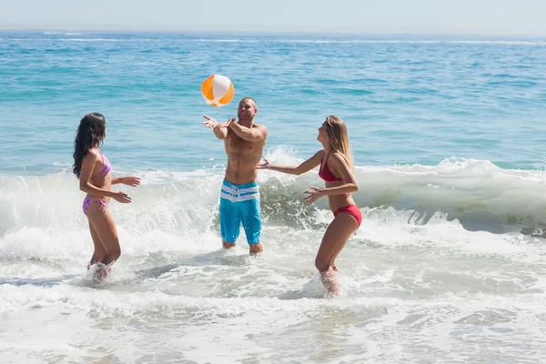 Amigos alegres brincando com uma bola de praia no mar — Fotografia de Stock