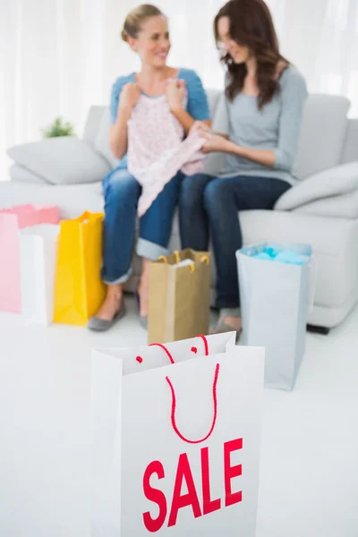 Friends with purchase and shopping bag on foreground — Stock Photo, Image