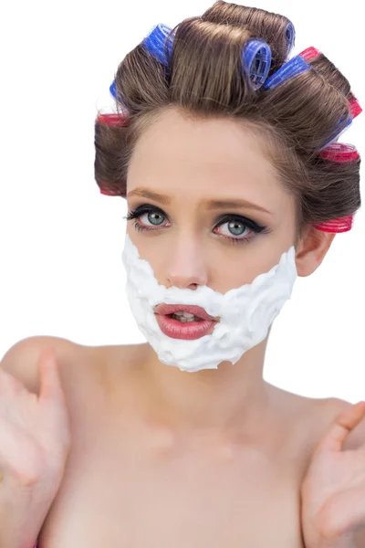 Surprised model in hair curlers posing with shaving foam — Stock Photo, Image