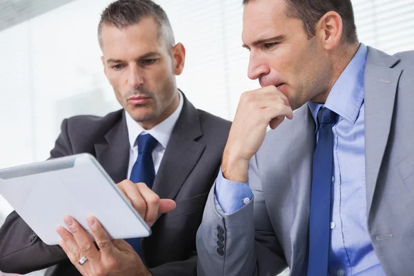 Empresários focados analisando documentos em seu tablet — Fotografia de Stock