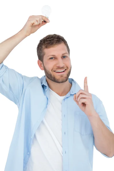 Smiling model holding a bulb above his head — Stock Photo, Image