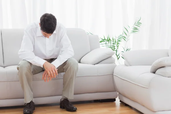 Проблемный молодой человек сидит на диване — стоковое фото