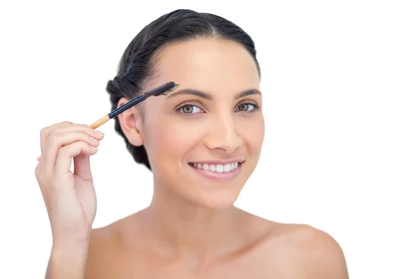 Smiling young brunette using eyebrow brush — Stock Photo, Image