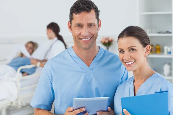 Portrait of surgeons with doctor attending patient on background — Stock Photo, Image