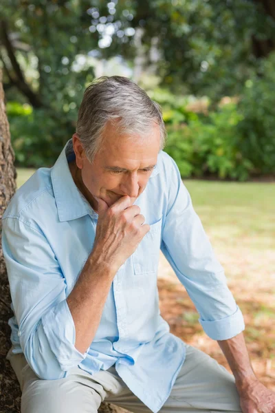 Doordachte gepensioneerde man zit op de boomstam met gebogen hoofd — Stockfoto