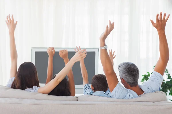 Семья смотрит телевизор и поднимает руки — стоковое фото