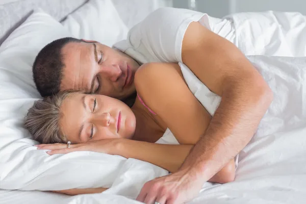 Χαριτωμένο ζευγάρι κοιμούνται και αγκαλιά στο κρεβάτι — Φωτογραφία Αρχείου