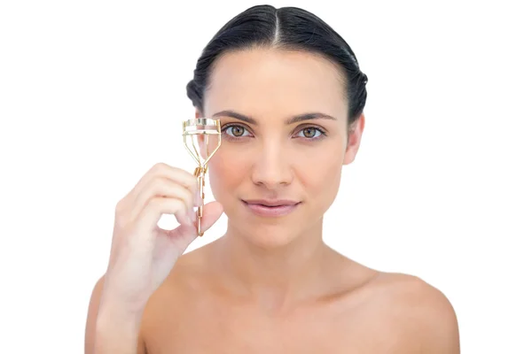 Smiling natural brunette holding eyelash curler — Stock Photo, Image