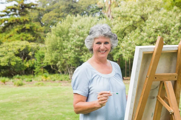 Усміхнена пенсіонерка малює на полотні — стокове фото