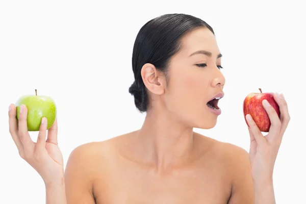 Schwarzhaariges Model, das Äpfel in beiden Händen hält und das rote O isst — Stockfoto