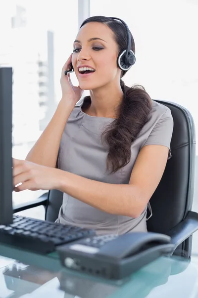 Attractive secretary wearing headset and pointing at computer sc — Stock Photo, Image