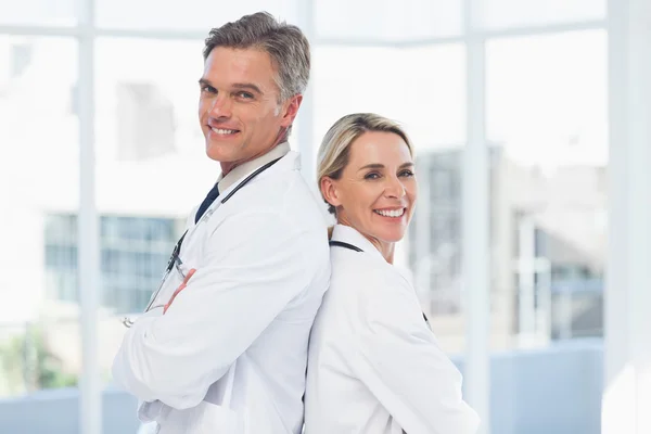 Smiling doctors posing together back to back — Stock Photo, Image