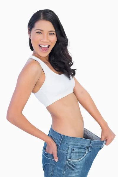Victorious woman holding her too big pants — Stock Photo, Image