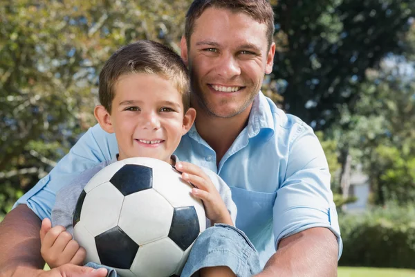 Feliz padre e hijo con un balón de fútbol en un parque Fotos De Stock