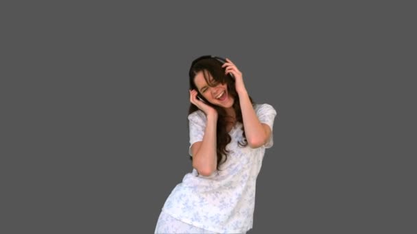 Happy young model in pyjamas listening to music — Stockvideo