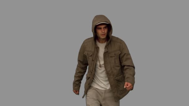 Man met een jas lopen naar camera op grijs scherm — Stockvideo
