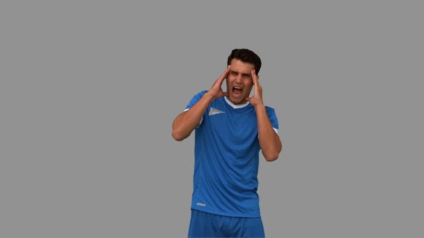 Jugador de fútbol que sufre de dolor de cabeza en pantalla gris — Vídeos de Stock