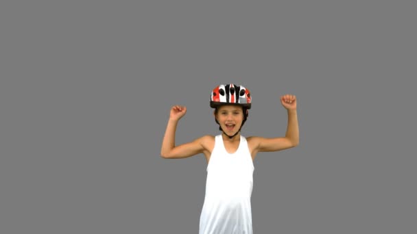 Leuk meisje dragen van een fiets helm en het verhogen van de armen op grijs scherm — Stockvideo