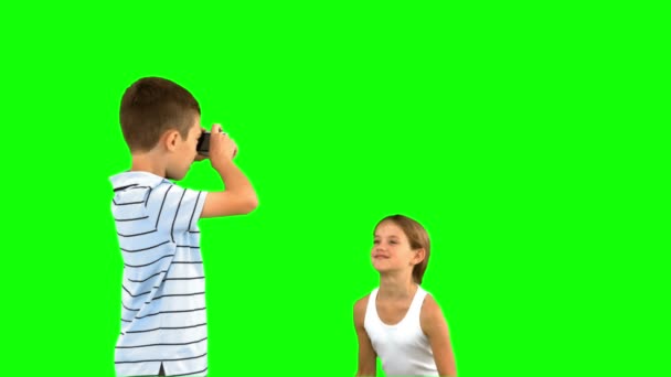 Brother taking pictures of his sister jumping on green screen — Stock Video