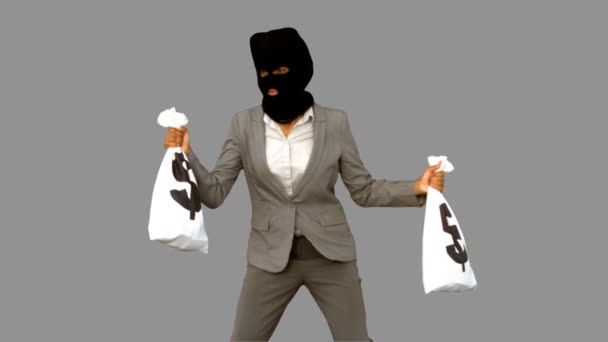 Burglar wearing balaclava and holding money bags on grey screen — Stock Video