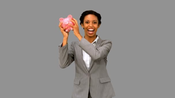 Businesswoman listening to a full piggy bank on grey screen — Stock Video