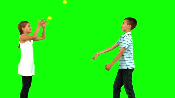 Siblings playing with tennis balls on green screen — Stock Video